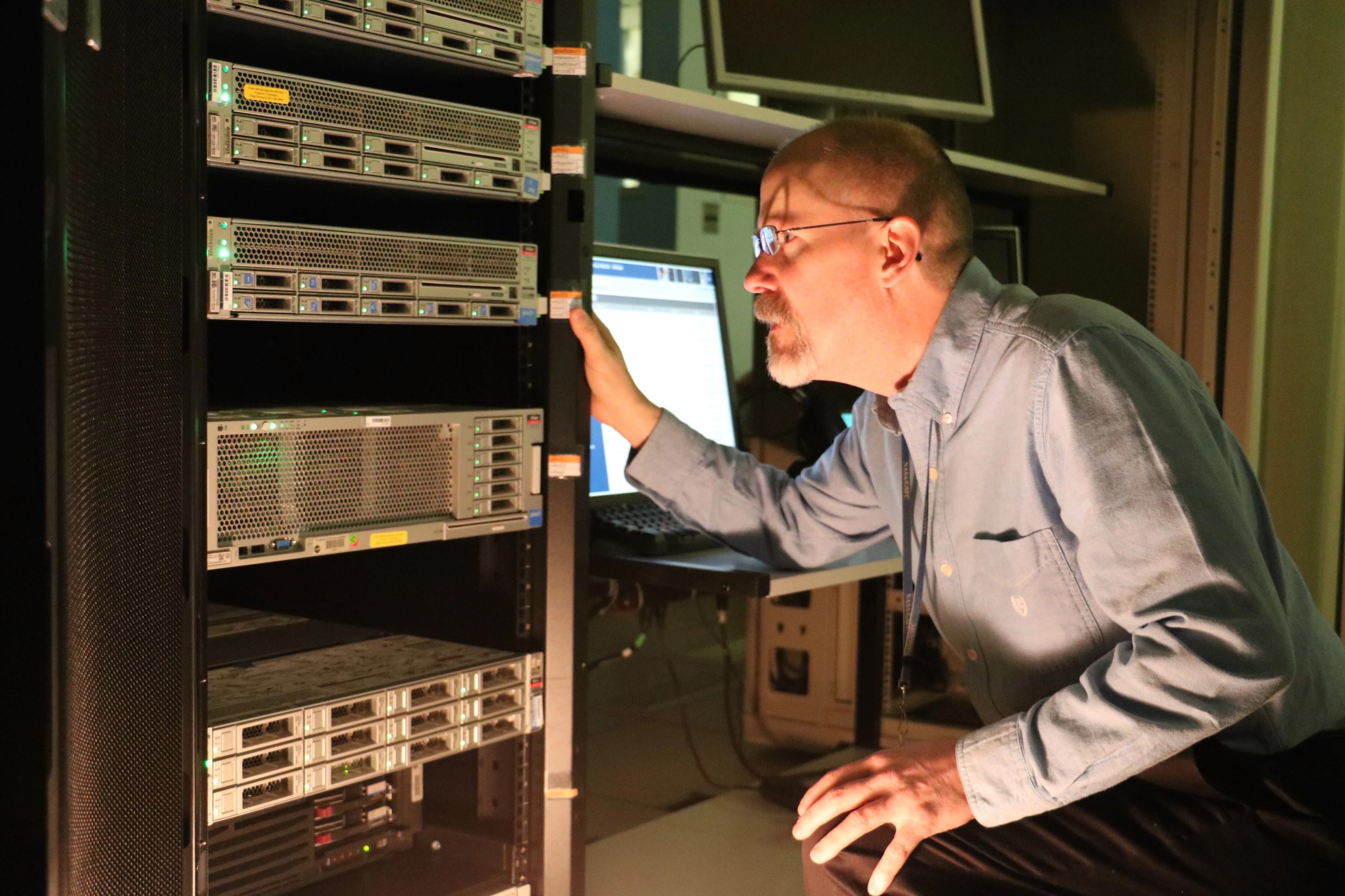 A man examines a shelf of computer hardware.