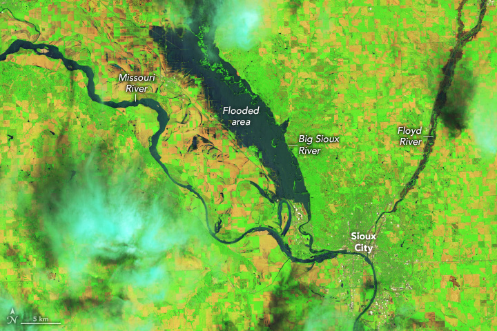 The vibrant green land, largely for farming surrounds the dark water that features in this image. There are three rivers, the Missouri meanders from the top left to the center bottom right, the Floyd from the top right converges with the Missouri in the same area and the Big Sioux coming down from the center top of the image and converges with the Missouri slightly to the left of the Floyd River. The Floyd is abnormally wide, but only at the upstream end, considering the narrow nature of the convergence area with the Missouri. The Big Sioux though has massively overflowed it's banks parallel to the Missouri and in broadened the banks of the Missouri somewhat where the rivers converge.