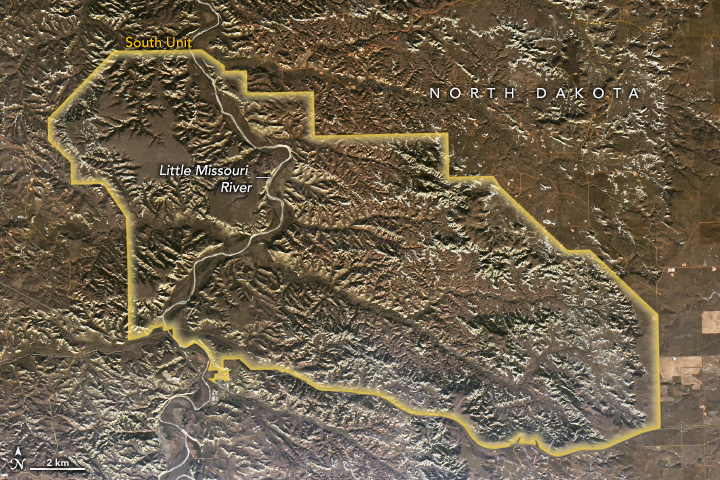 Outline overlaid on satellite image of North Dakota of the South Unit of the "badlands" with visibly rocky terrain and white capped peaks and numerous craggy valleys, with the Little Missouri River meandering through the western region on the South Unit