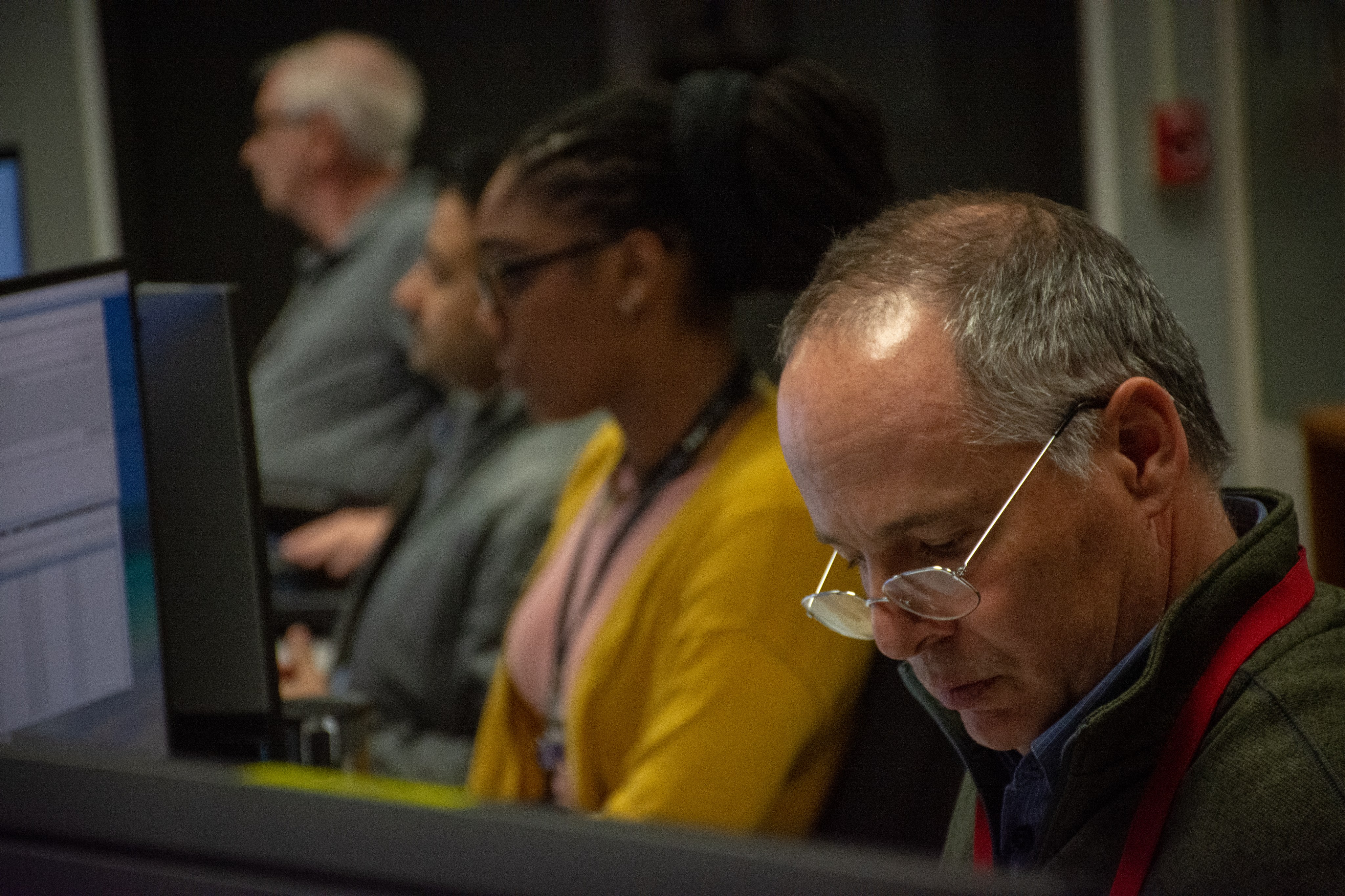 A Hubble flight controller looks down at written operations procedures while at his console.