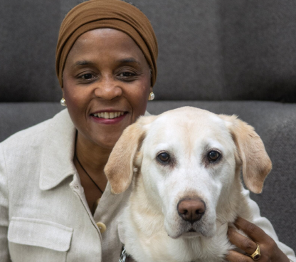 Seeing Eye Chair and Graduate Cynthia Bryant smiling and hugging her yellow Labrador/golden retriever cross.