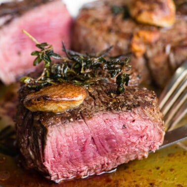 perfectly cooked filet mignon steak cut in half with garlic and herbs