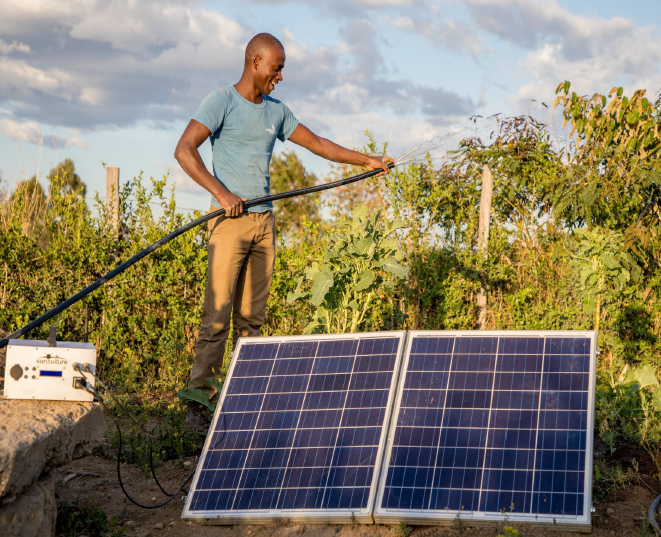 Man with Sunculture solar irrigation system waterin plants