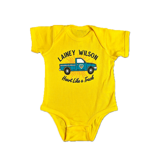 Yellow baby onesie with ’Lainey Wilson Heart Like a Truck’ text and a blue pickup truck graphic.