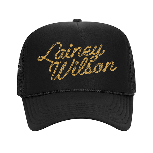 Black trucker hat with ’Lainey Wilson’ embroidered in gold script on the front.