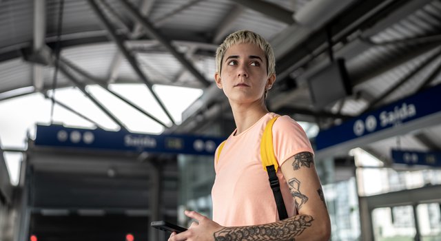 tattooed-woman-holds-phone-in-train-station.jpg