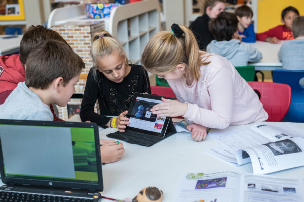 kinderen werken in klas gezamenlijk aan tablet