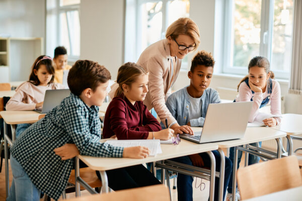 juf geeft uitleg aan kinderen op laptop