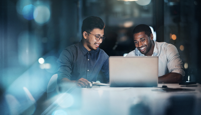 Cropped shot of two young businessmen working together on a laptop in their office late at night