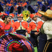 A young woman swings her colorful Jalisco style dress while dancing with a man in a sombrero