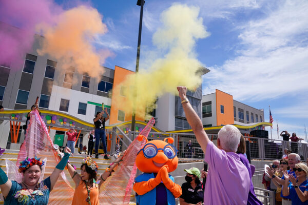 Colored smoke goes off as people cheer and clap in front of the MAC building.