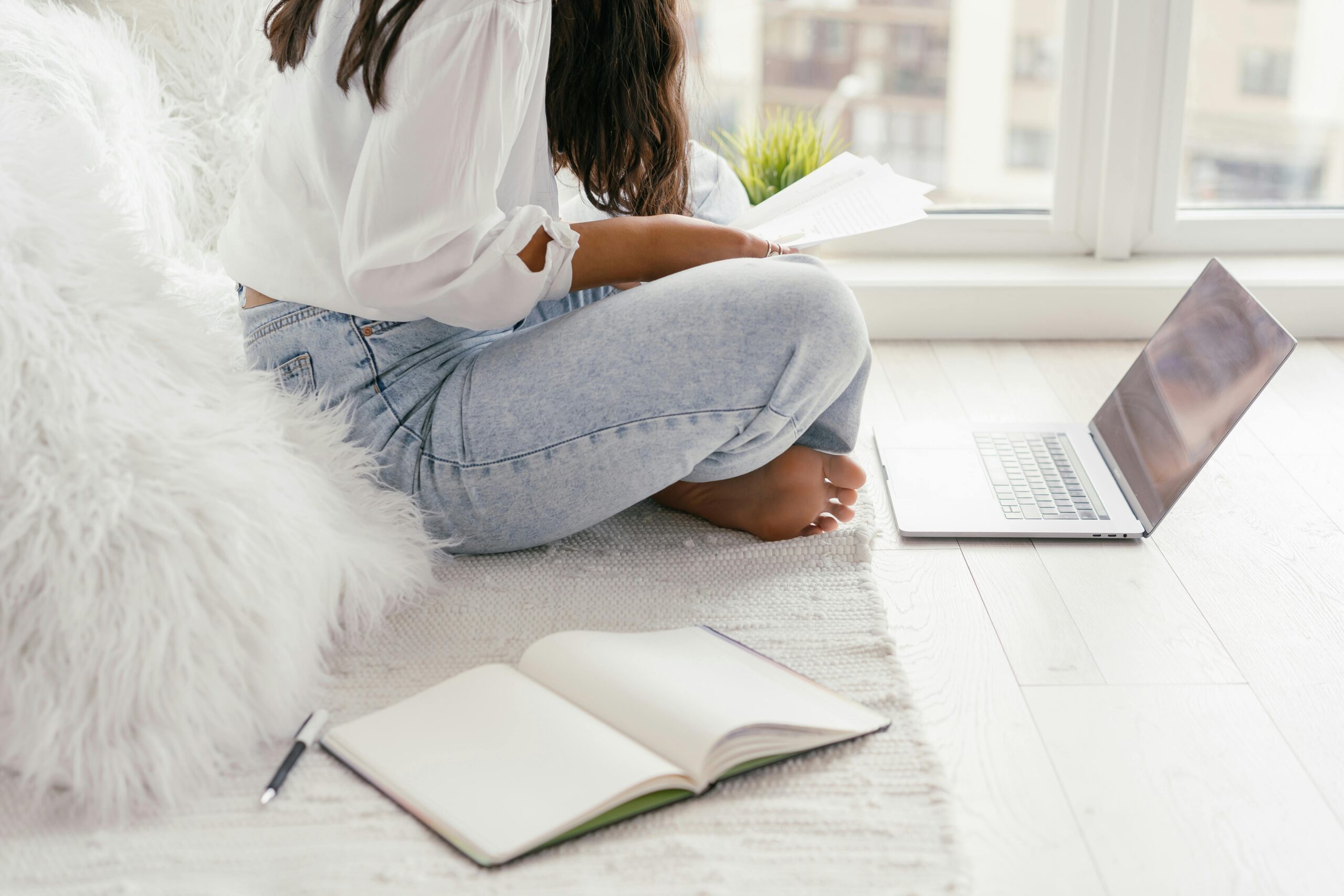 a college student studying on her laptop with a notebook open