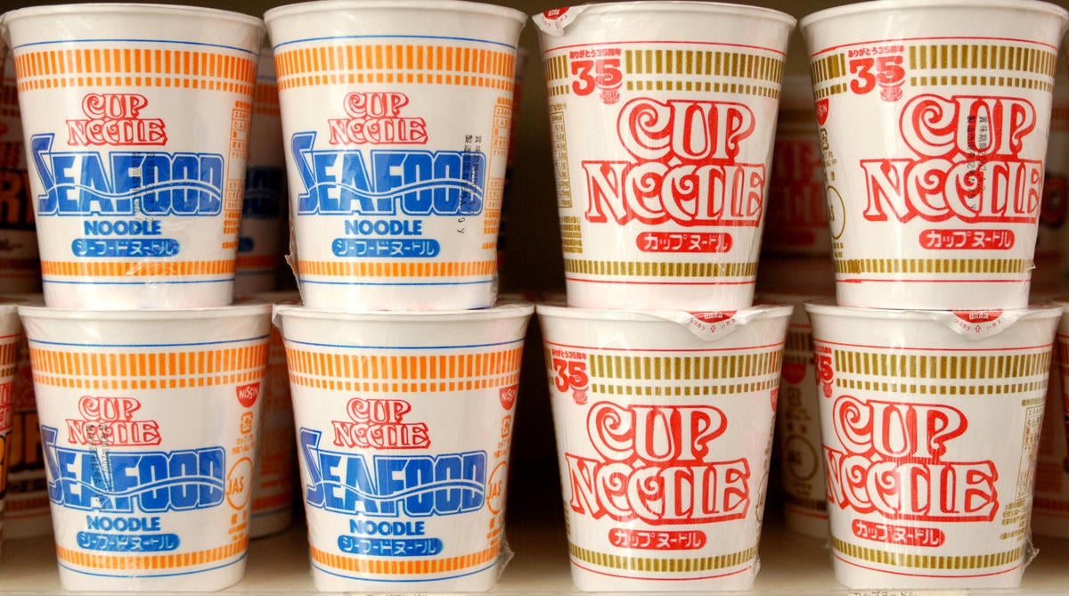 Cup noodles made by Nissin Food Products Co. sit on a shelf