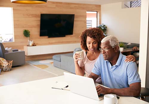 Retired Elderly Couple Using Laptop To Enroll In Medicare