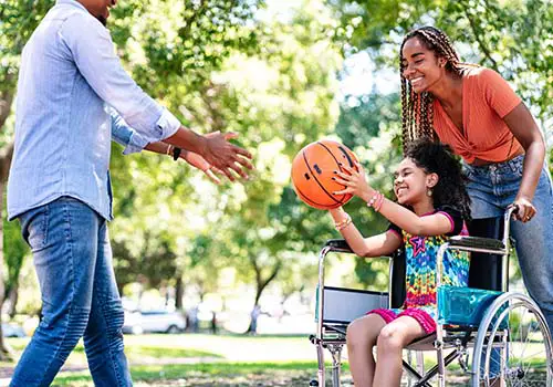 Girl In A Wheelchair Playing Basketball With Her Family