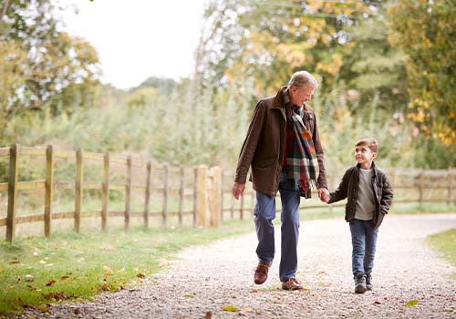 Grandfather Walking Through Countryside With Grandson