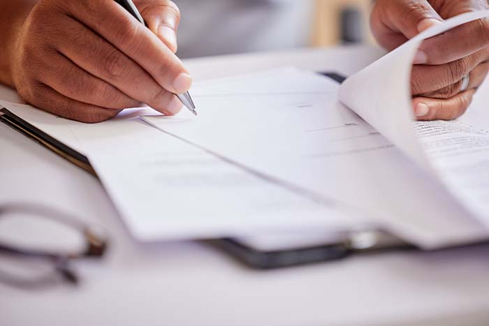 Cropped image of a man filling out paperwork for the Medicare Give Back Benefit.