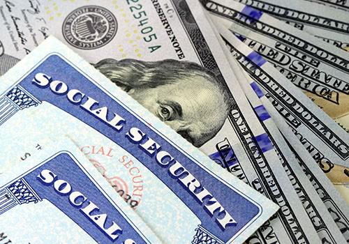 Social security cards on top of hundred dollar bills.