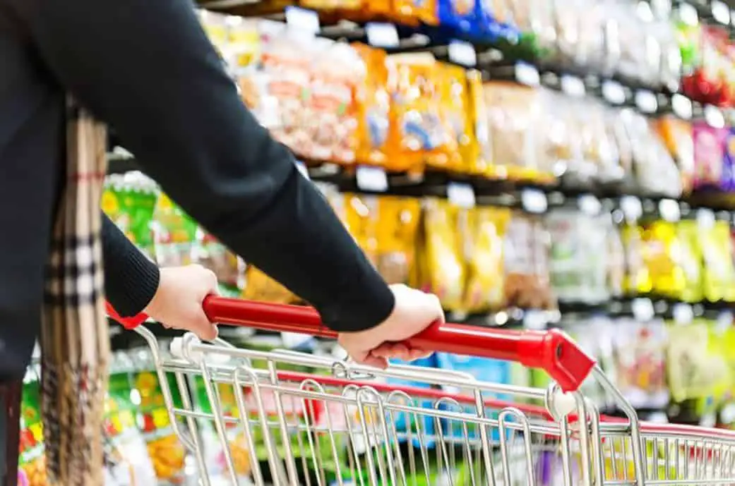 A man pushing a shopping cart around a grocery store.