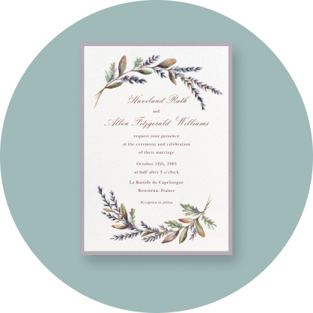 A white invitation with two leafy sprigs creating a border on a light blue backdrop.