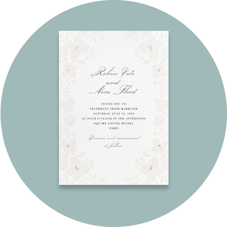 A white invitation with an embossed floral border on a light blue backdrop.