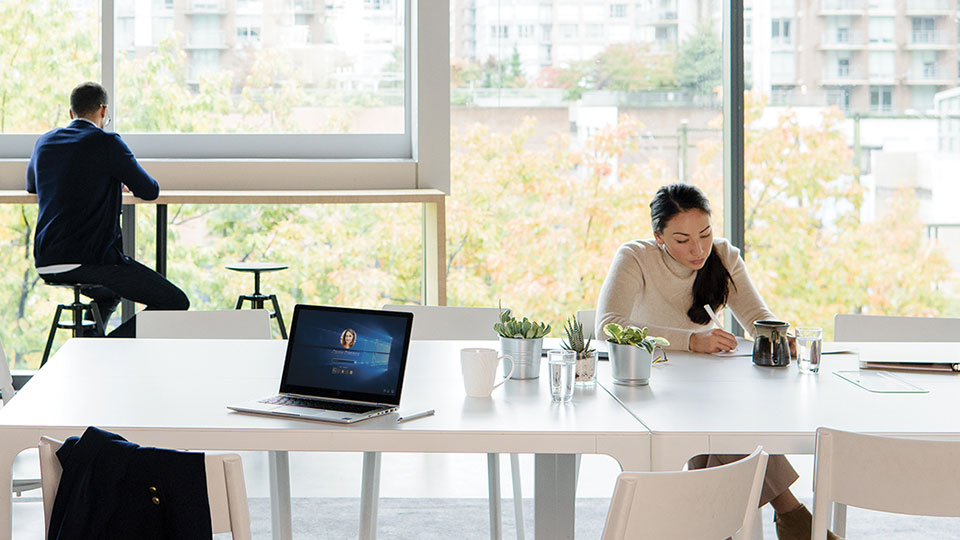 Two people work separately in a communal workspace