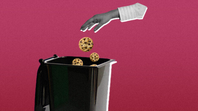 a hand dropping cookies into a garbage can