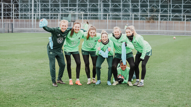 Trainingsauftakt bei den VfL-Frauen. 5 Spielerinnen stehen in einer Reihe, sie haben ihren Arm jeweils auf der Schulter der anderen liegen. Links daneben ebenfalls vom VfL ein Mann der mit eingereiht ist. Alle lachen in die Kamera.