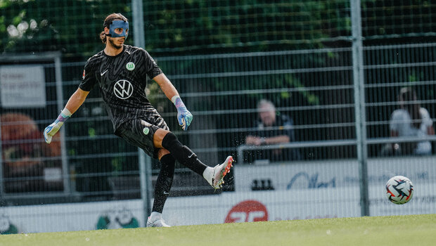 VfL Wolfsburg Torwart Kamil Grabara, der eine Maske im Gesicht trägt, beim Abstoß im Testspiel gegen Lille OSC.