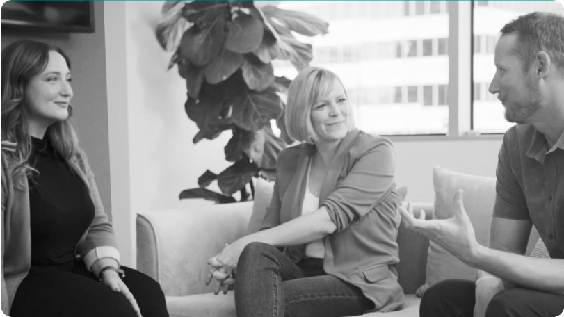 Three colleagues chat on a couch 