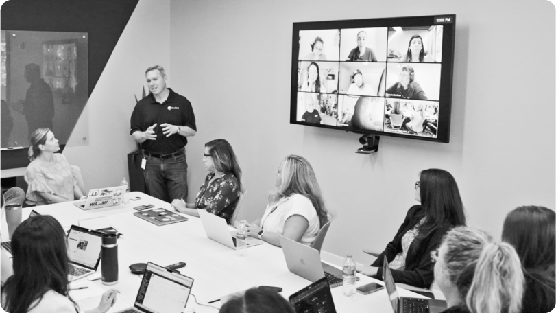 A table of colleagues watch a speaker in a conference room 