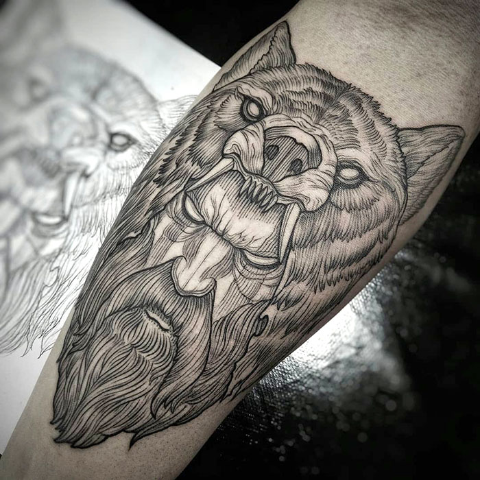 Detailed Viking tattoo featuring a fierce wolf and a bearded warrior on an arm.