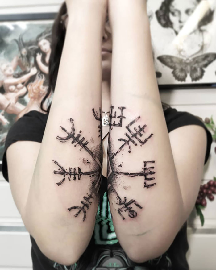 Person displaying intricate Viking tattoos on both forearms, featuring runic symbols.