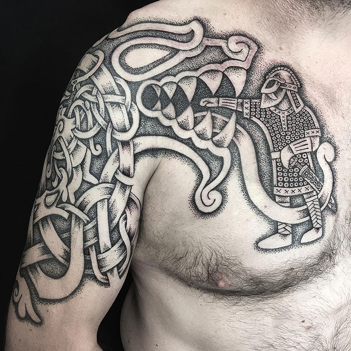 Intricate Viking tattoo depicting a warrior and beast on a person's chest and shoulder.