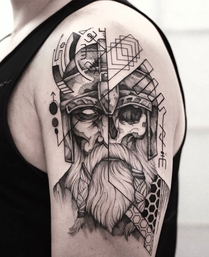 Viking tattoo on arm features a detailed warrior helmet and beard design.