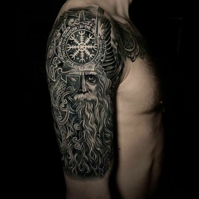 Detailed Viking tattoo of a bearded warrior with a helmet on an arm, showcasing intricate patterns.