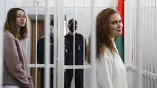 Journalists Katsiaryna Andreyeva, right, and Daria Chultsova stand inside a defendants' cage in a court room in Minsk, Belarus, Thursday, Feb. 18, 2021.