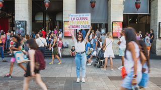 Diana Dimitrova, a Ukrainian from Kyiv holds a poster that reads in French 'For those who have forgotten: the war in Ukraine is still ongoing'. Lyon, France. August 2022