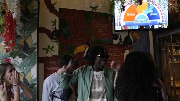 People in a Paris cafe watching the television as they react to the projection of results during the second round of the legislative elections, July 7, 2024