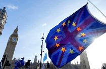 EU and UK flags are flown together at a protest in London's Parliament Square.