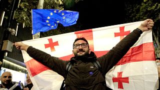 Un hombre sostiene una bandera georgiana durante un mitin de la oposición en Tiflis, 20 de octubre de 2024.