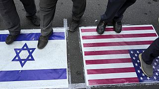 FILE - Iranian demonstrators stand on U.S. and Israeli flags in an anti-Israeli gathering at Felestin (Palestine) Square in Tehran, Iran, Tuesday, Oct. 8, 2024