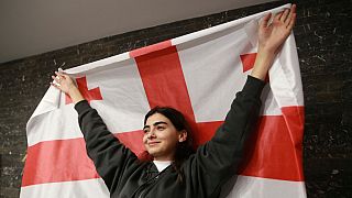 A supporter of the Coalition for Change holds a Georgian flag at coalition's headquarters after polls closing at the parliamentary election in Tbilisi, Georgia, 2024.