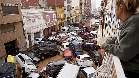 Une femme regarde de son balcon les véhicules coincés dans la rue lors des inondations à Valence.