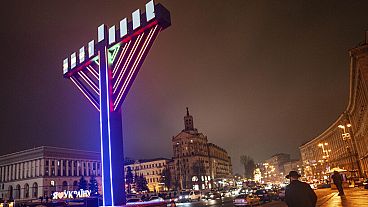 A man walks past menorah after lighting candles marking the fifth night of the Jewish holiday of Hanukkah on Independence square in Kyiv, Ukraine, Monday, Dec. 11, 2023