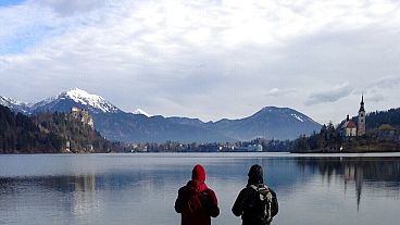  In this photo taken Tuesday, Jan. 27, 2015, people stand by the Lake Bled in Slovenia with a island and the Church of Our Lady on it.