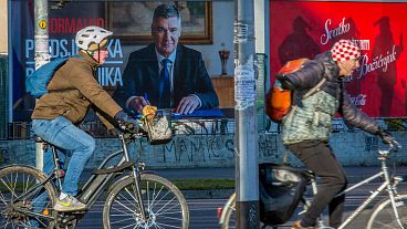 Cyclists ride past a poster of incumbent President Zoran Milanovic ahead of the presidential election in Zagreb, Croatia, Thursday, 26 December 2024