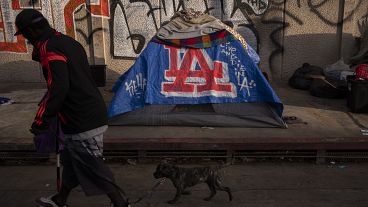 FILE - A man walks past a homeless encampment in downtown Los Angeles, Wednesday, Oct. 25, 2023. (AP Photo/Jae C. Hong, File)