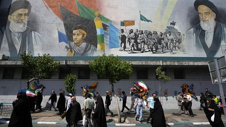 I fedeli iraniani passano davanti a un murale raffigurante l'ayatollah Ali Khamenei, a sinistra, dopo la preghiera del venerdì a Teheran, 19 aprile 2024