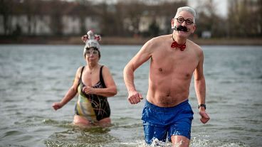 Des personnes participent à la baignade annuelle du Nouvel An avec le club de natation d'hiver "Seehunde Berlin", au lac Oranke à Berlin, le 1er janvier 2025.